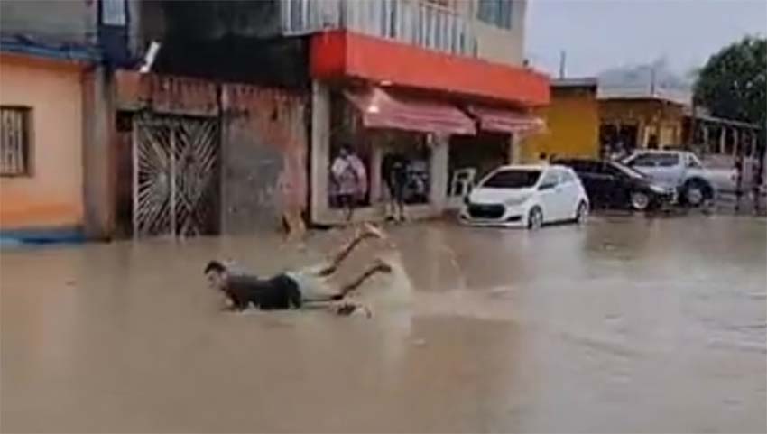 ‘Igarapé do Passarinho’ transborda e homem mergulha em rua alagada no bairro Monte das Oliveiras