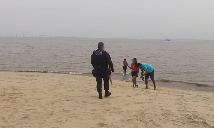 Descumprindo interdição, grupo de banhistas é orientado a sair da praia da Ponta Negra na extrema vazante do rio
